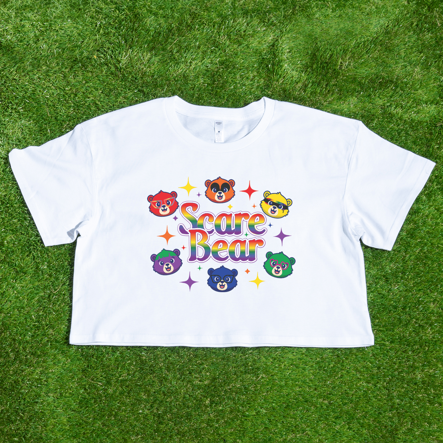 The SCARE BEAR fundraiser tee is a white crop top featuring colorful cartoon bear faces, "Scare Bear" in rainbow letters, and sparkling stars—locally hand printed and perfect for a fun squad or roller derby shirt.