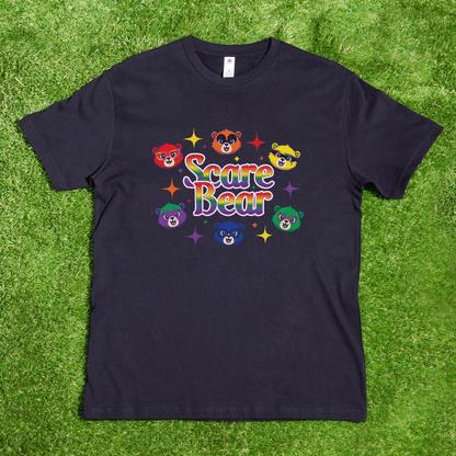 A black SCARE BEAR fundraiser tee—a locally hand-printed t-shirt—lies on grass with colorful cartoon bear faces and rainbow "Scare Bear" text; perfect for roller derby, GAY SKATE, or showing your pride.