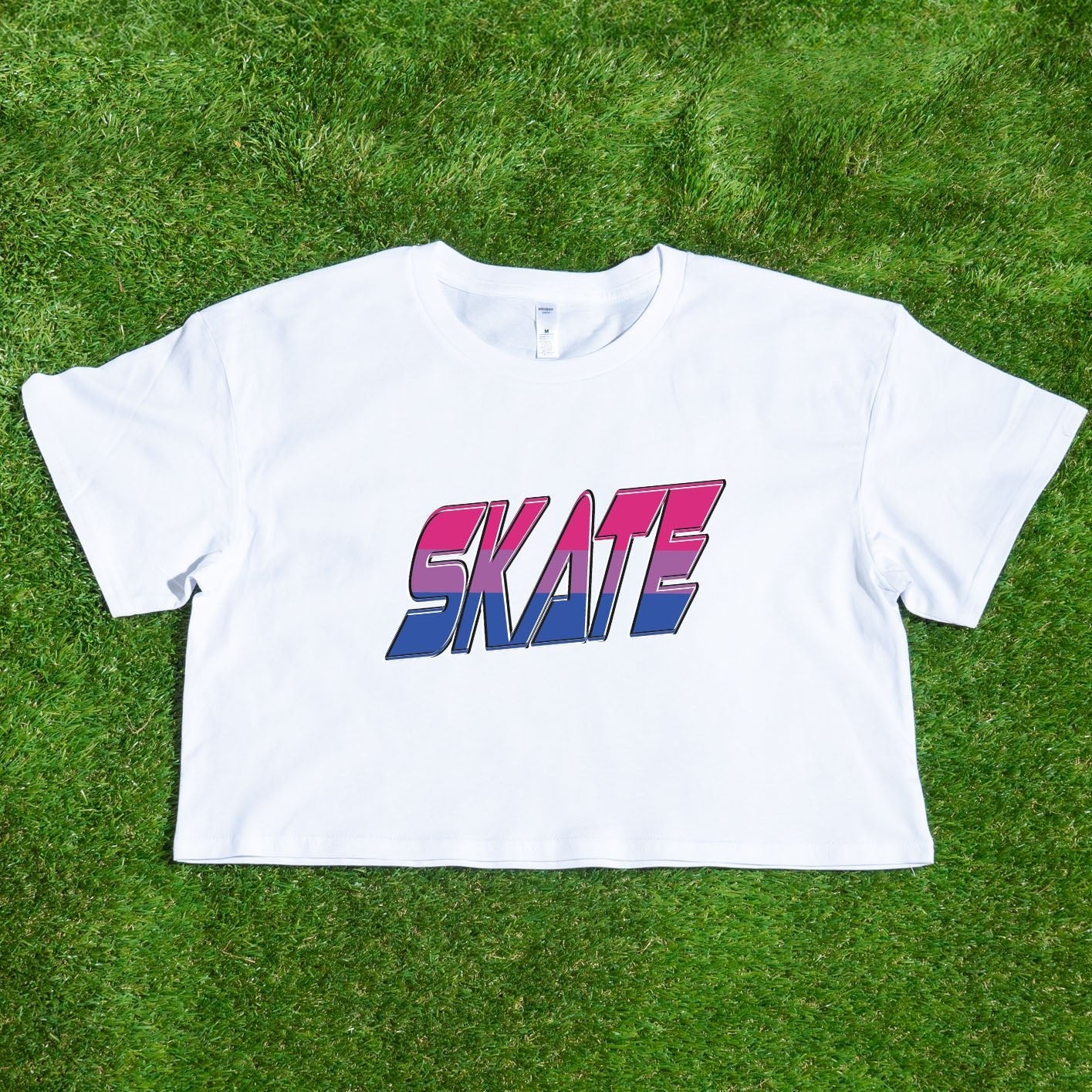 The "SKATE bisexual pride flag - locally printed crop tee" by Gay Skate is a black cropped T-shirt featuring the word "SKATE" printed across the front in a bold, gradient design that transitions from red at the top to pink, purple, and blue at the bottom. Perfect for Queer Skate events, it showcases text with a slightly 3D effect and a retro, angular font style.