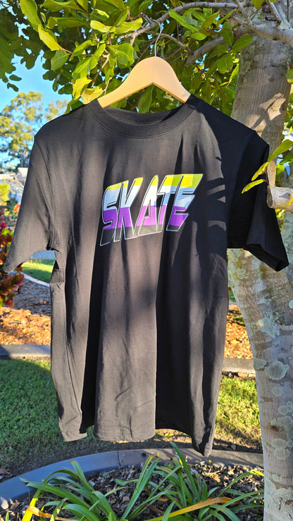 The "SKATE Non-Binary Flag - Local hand printed t-shirt" from My Store, displayed outdoors hanging on a tree branch, showcases the word "SKATE" in large, bold letters adorned with a stunning gradient of yellow, purple, and blue. This vivid design celebrates diversity and stands out beautifully against the lush greenery on a sunny day.