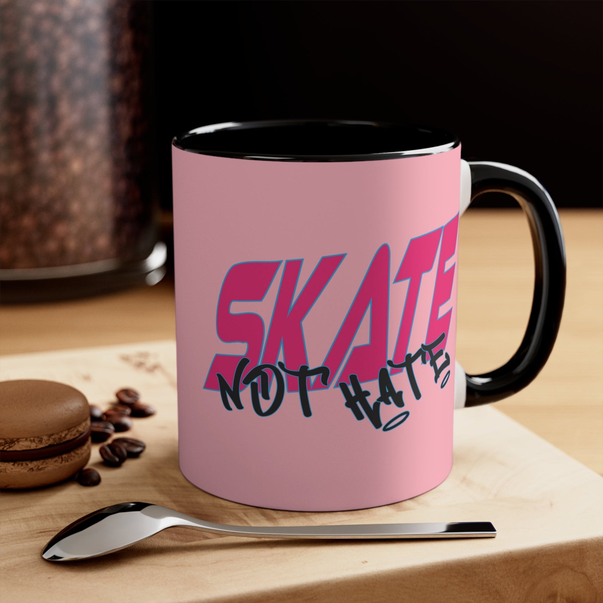 The Skate Not Hate accent mug by Printify is a white ceramic coffee mug featuring an eye-catching pink background and black handle. The design includes bold pink and blue text that reads "SKATE" paired with black graffiti-style text below it that reads "NOT HATE." This stylish mug makes a powerful statement against hate.