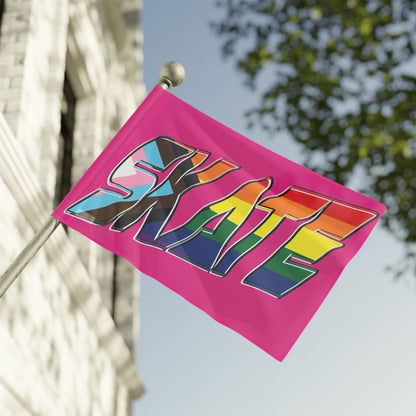 Gay Skate's SKATE progress pride original logo flag - on pink features a bold graphic with the multicolored rainbow pride word "SKATE" on a vibrant pink background. The letters are adorned in the colors of both the rainbow flag and the transgender pride flag, celebrating inclusivity and queer skating pride within the community.