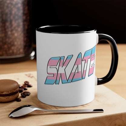 This SKATE trans pride flag accent mug by Printify features a white ceramic base with a blue handle and matching colorful interior. The word "SKATE" is emblazoned in bold letters, styled with vibrant pink and blue tones. Hand wash only to maintain its vivid design.