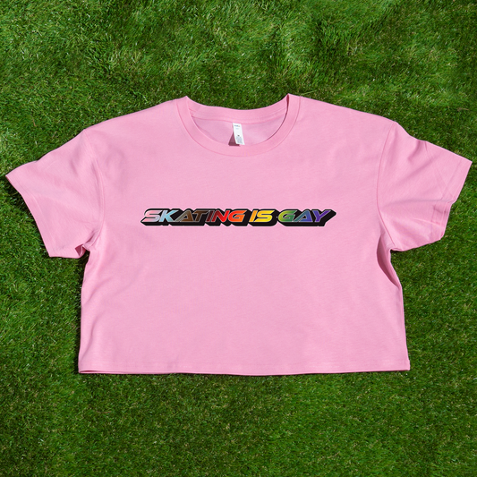 A locally printed crop tee by Gay Skate, featuring short sleeves and a bold "SKATING IS GAY" slogan in rainbow gradient letters across the chest, perfect for celebrating queer skate culture.