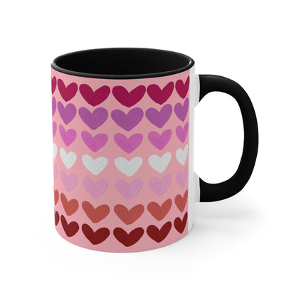 The "Subtle Lesbian Pride Flag - love hearts - colourful accent mug" by Printify is a white ceramic mug with a vibrant interior and red handle, adorned with heart patterns in various shades of pink, purple, and red. The hearts are arranged in horizontal rows, gradually transitioning from lighter shades at the top to darker ones at the bottom.