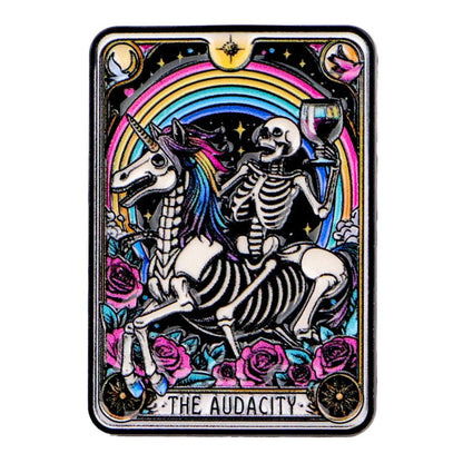 Tarot Card enamel pin featuring a skeleton on a unicorn with a rainbow and roses, labeled 'The Audacity'.