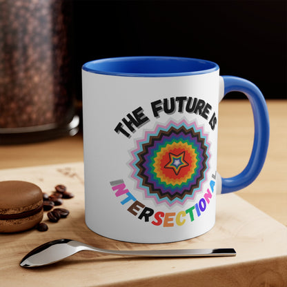 The Future Is Intersectional - original design - colourful accent mug by Printify is a white mug with a blue handle and interior, featuring an original star-shaped pattern in vibrant colors at the center. The text "THE FUTURE IS" appears above the pattern, and "INTERSECTIONAL" is displayed below in rainbow-colored letters, creating an eye-catching color contrast.