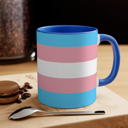 The Trans Pride Flag Colourful Accent Mug by Printify features a ceramic design with horizontal stripes in blue, pink, and white. Its solid blue handle perfectly complements the colorful interior.