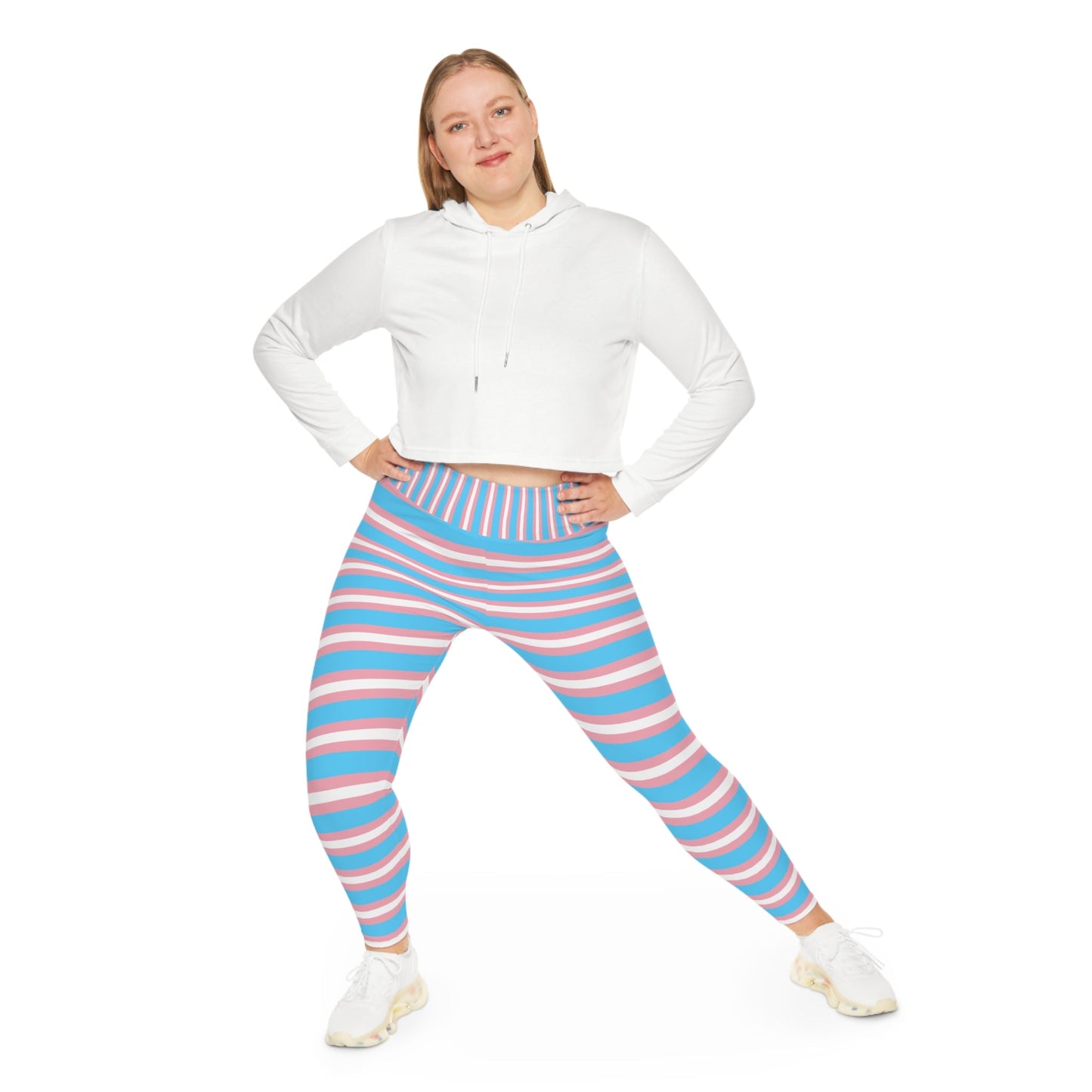 A person is modeling vibrant Trans Pride Plus Size Leggings (available in sizes 2XL - 6XL), featuring horizontal stripes in blue, pink, and white to represent transgender pride. The leggings are coordinated with white sneakers against a plain white background. The image focuses solely on the lower body, excluding the upper body and face.