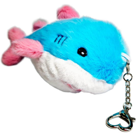 Trans Pride Shark plushy keychain with a blue body, pink fins, and a white belly, attached to a silver heart-shaped carabiner.