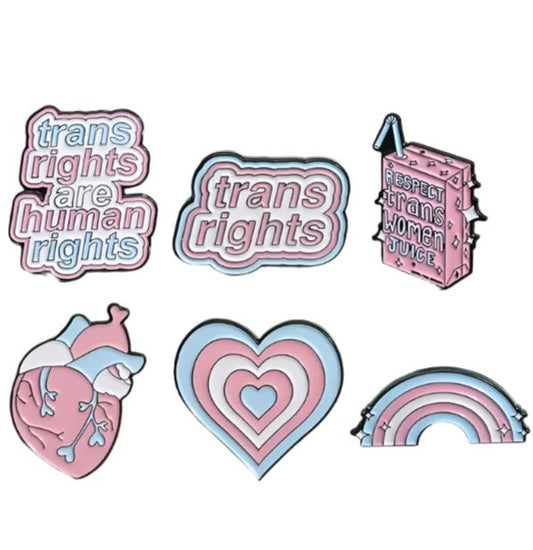 Product Description: The "Trans Rights and Trans Pride" enamel pins collection by Gay Skate includes six beautifully designed badges celebrating transgender pride. Top row designs feature: "Trans Rights Are Human Rights," "Trans Rights," and "Respect Trans Women Juice." Bottom row designs include an anatomical heart with trans flag colors, a heart with layered trans flag colors, and a rainbow with trans flag colors.