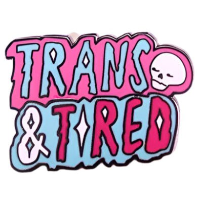 The Gay Skate "Trans & Tired" enamel badge features a bold design with a cartoon skull and the words "Trans & Tired," incorporating vibrant pink and blue colors representative of transgender pride.