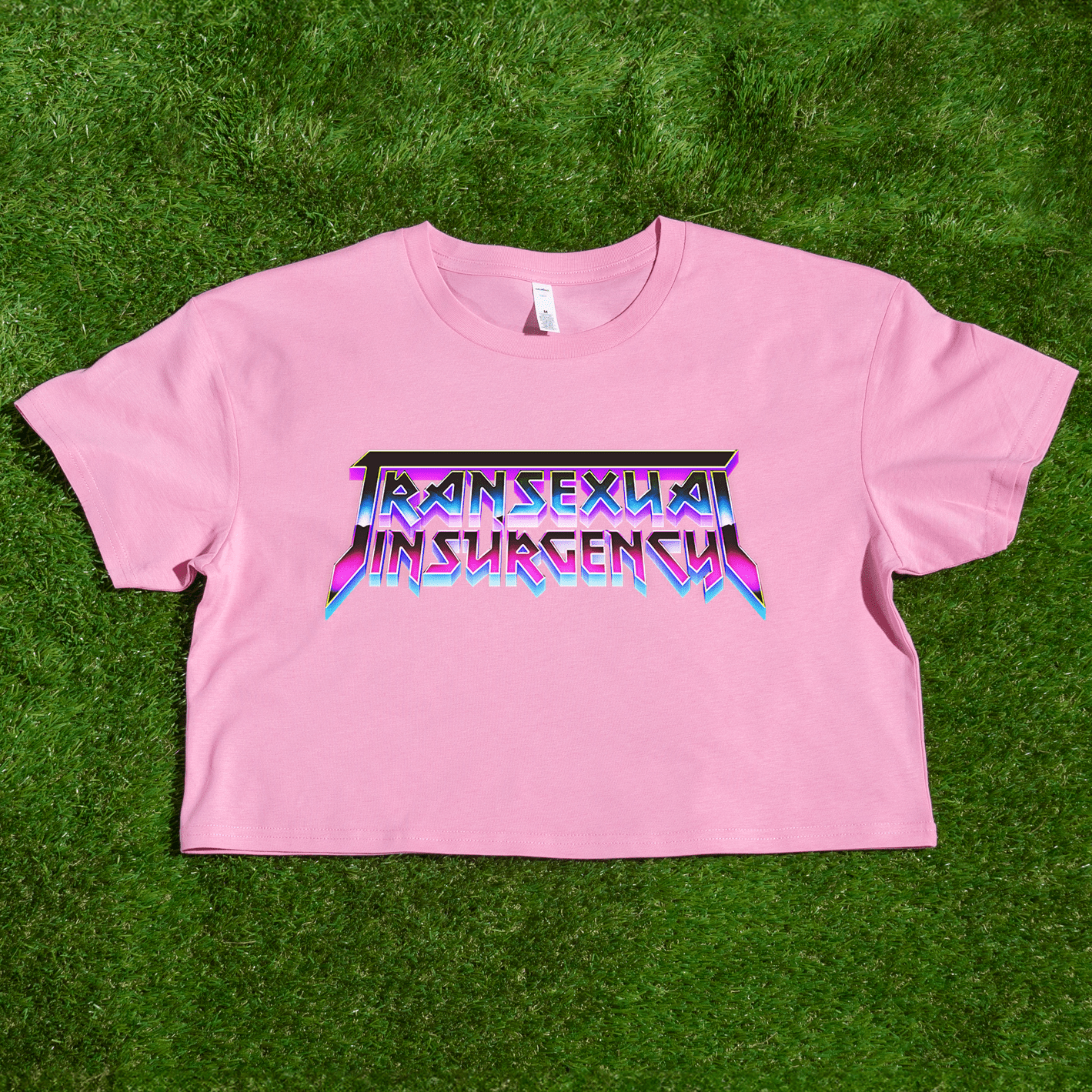 Pink crop top with 'Transsexual Insurgence' text on a grass background