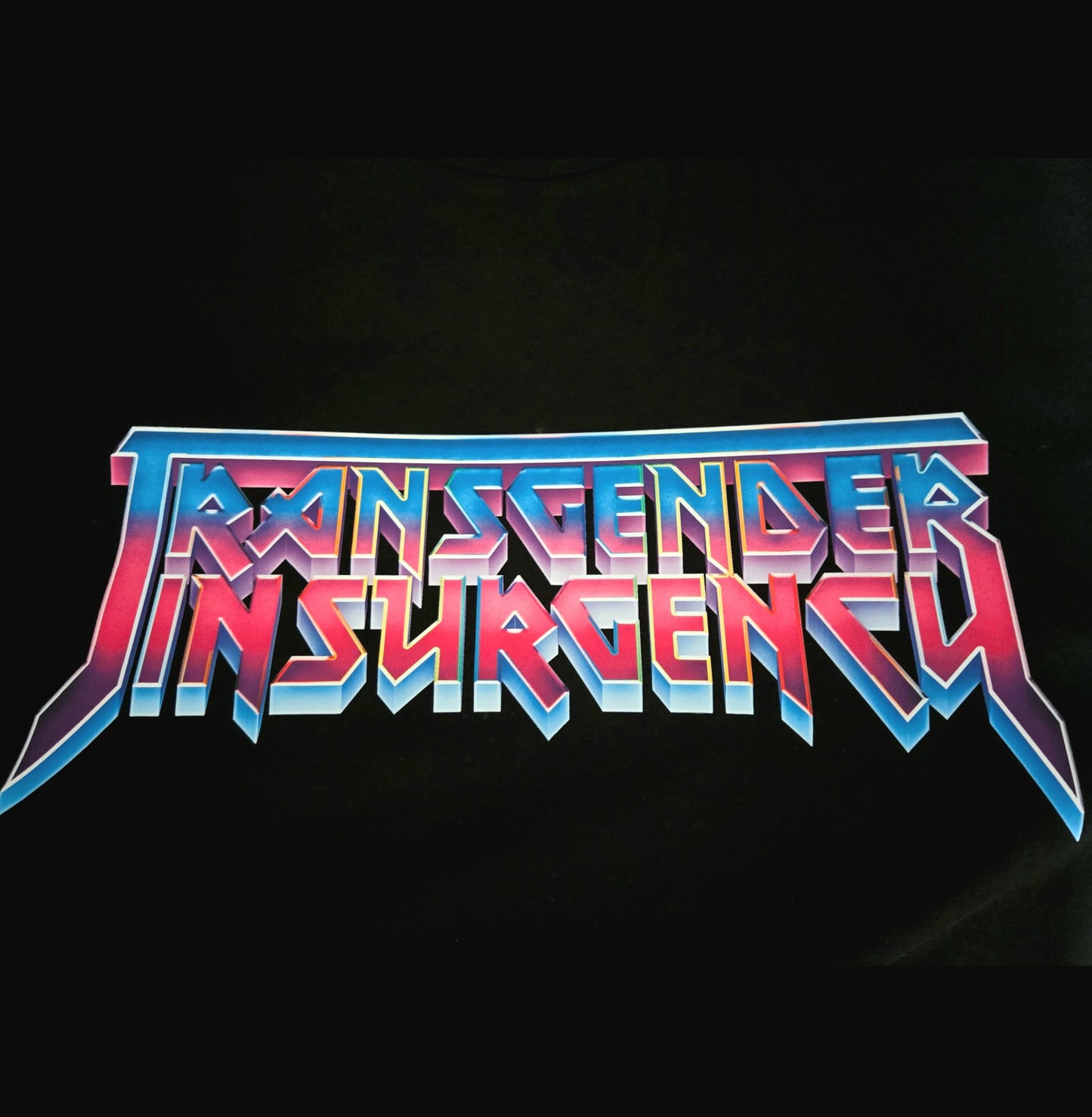 The words "Transgender Insurgency" appear in bold, angular, retro-style lettering with blue, pink, and purple gradients on a black background on the "Transgender Insurgency and Transexual Insurgency" locally hand-printed t-shirt.
