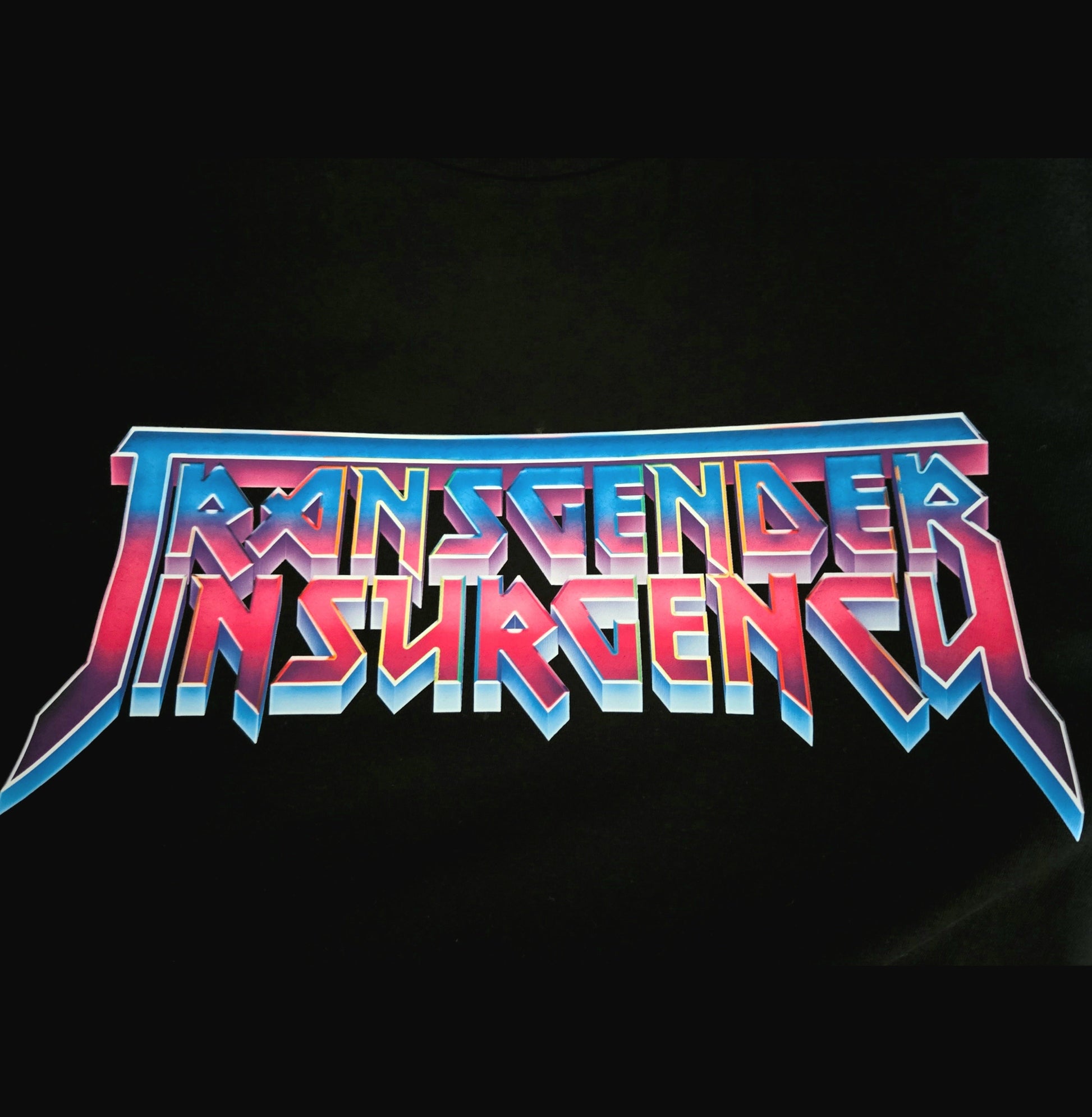 The words "Transgender Insurgency" appear in bold, angular, retro-style lettering with blue, pink, and purple gradients on a black background on the "Transgender Insurgency and Transexual Insurgency" locally hand-printed t-shirt.