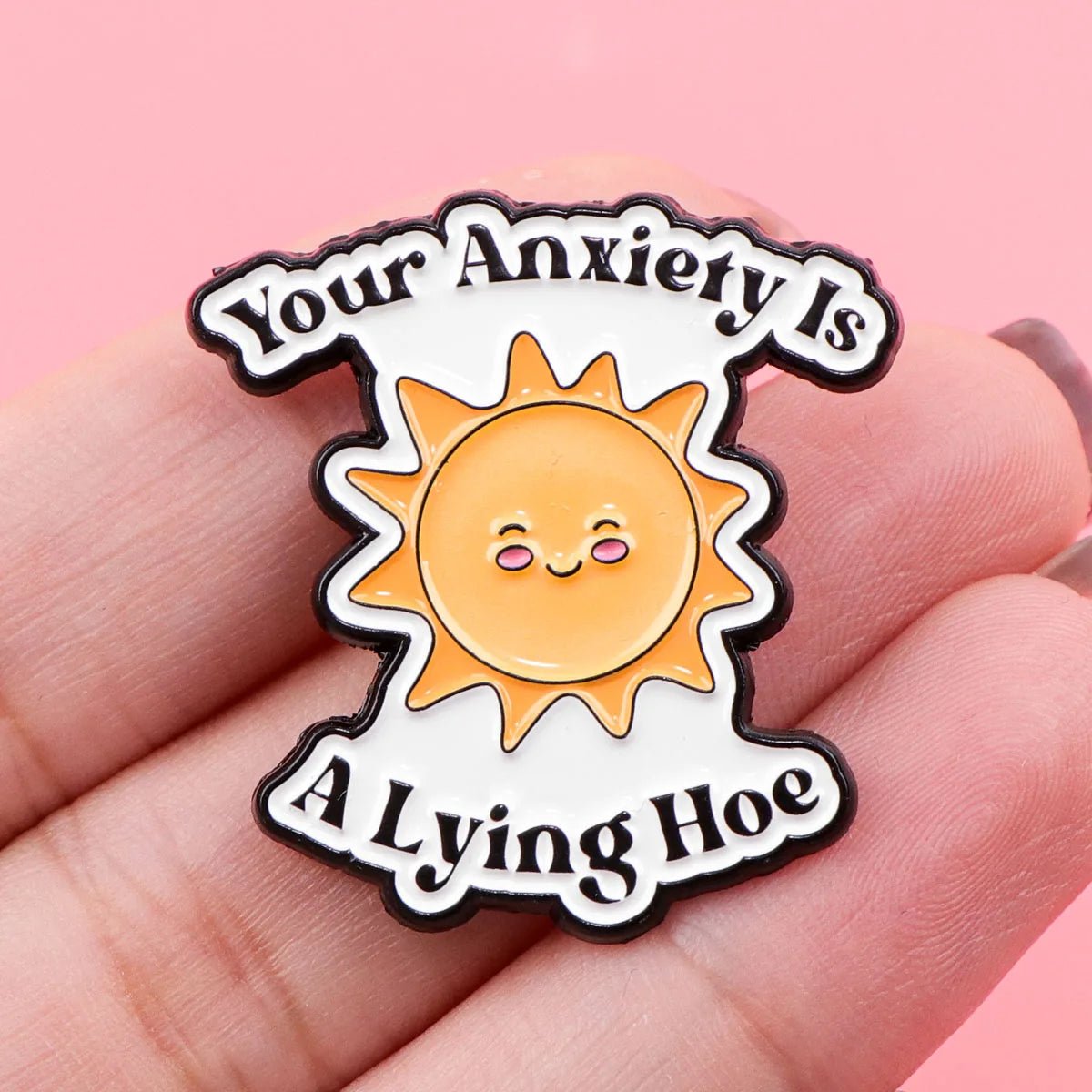 Mental health Pin with sun design and text 'Your Anxiety Is A Lying Hoe' held in hand against pink background