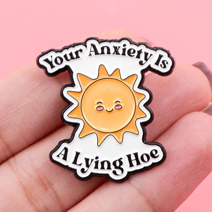 Mental health Pin with sun design and text 'Your Anxiety Is A Lying Hoe' held in hand against pink background